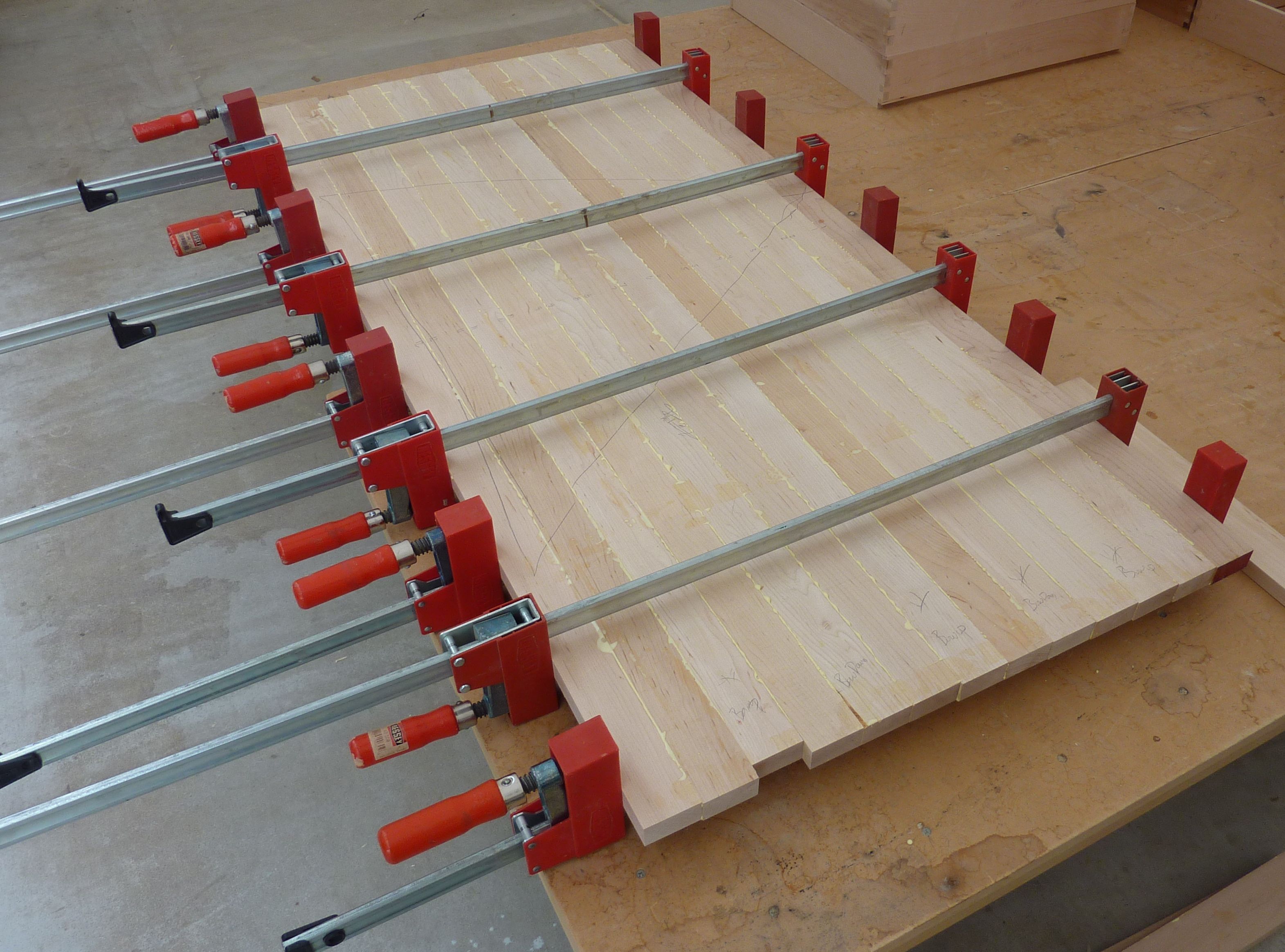 Bar clamps holding a wooden tabletop glue-up